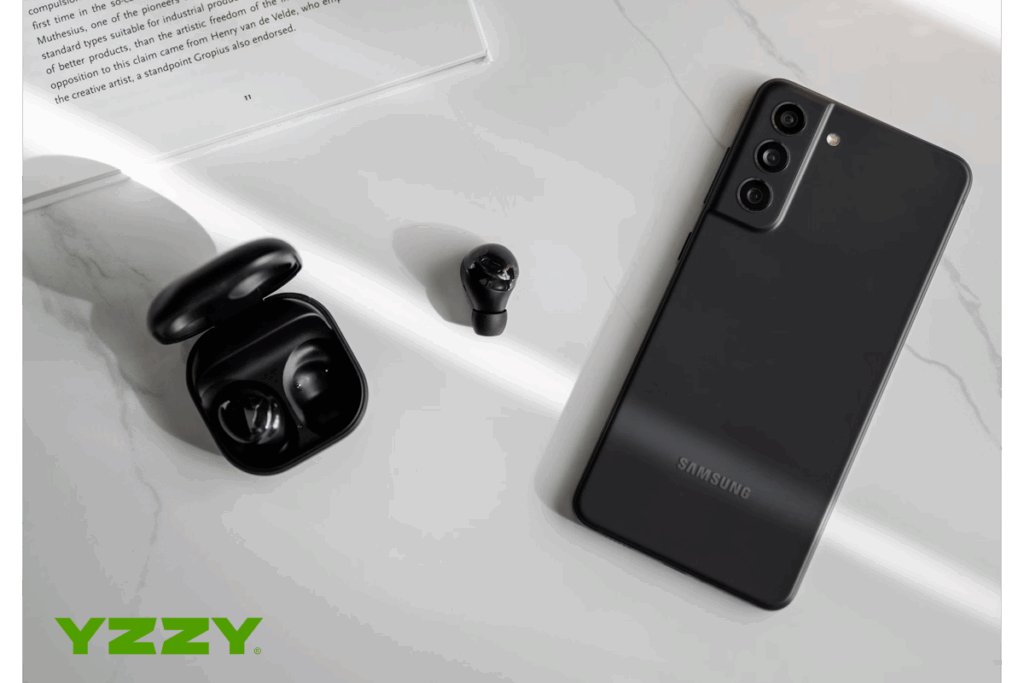 telefon amsung negru pe o masa langa casti flori document